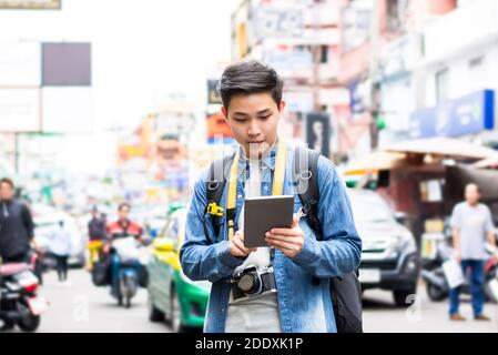 Asiatische Fotograf Tourist Backpacker mit Tablet, um Position zu finden, während Reisen im Urlaub in Khao San Road Bangkok Stadt Stockfoto