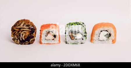 Vier Maki-Rollen in einer Reihe mit Lachs und Gurke auf weißem Hintergrund. Frische Hosomaki-Stücke mit Reis und Nori. Nahaufnahme von leckeren japanischen Essen wi Stockfoto