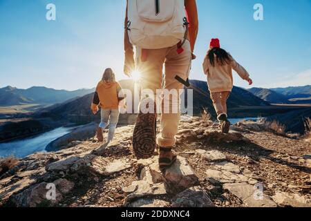 Drei junge Touristen Wanderer Spaziergänge gegen Sonnenuntergang Berge und Fluss Stockfoto