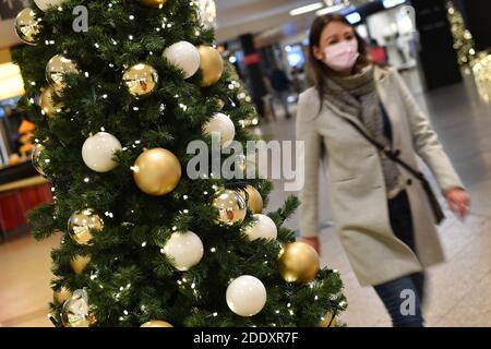 Thema Bild Gefangene in der Coronavirus-Pandemie am 26. November 2020. Eine junge Frau mit Gesichtsmaske, Maske geht an einem Weihaftertsbaum in einem Einkaufszentrum vorbei. Pandemie, Sperrung, Abschaltung, Inzidenzwert. MODELL FREIGEGEBEN! Weltweite Nutzung Stockfoto