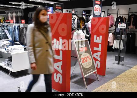 Themenbild SCHWARZ FREITAG am 26. November 2020. Eine junge Frau mit Gesichtsmaske, Maske kommt aus einem Modehaus. Daneben sind Schilder und Displays VERKAUF, RABATT. Pandemie, Sperrung, Abschaltung, Inzidenzwert. MODELL FREIGEGEBEN! Weltweite Nutzung Stockfoto