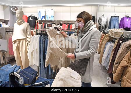 Themenbild SCHWARZ FREITAG am 26. November 2020. Eine junge Frau mit Gesichtsmaske, Maske schaut auf Textilien, Kleidungsstücke in einem Modegeschäft in Zeiten der Corona-Pandemie, Sperrung, Abschaltung, Inzidenzwert. MODELL FREIGEGEBEN! Weltweite Nutzung Stockfoto