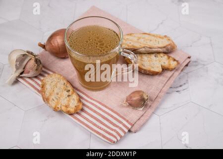 Fleischbrühe im Glas Tasse auf Serviette zum Mittagessen auf hellem Hintergrund. Stockfoto