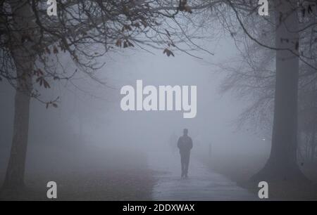 Im war Memorial Park in Basingstoke, Hampshire, ziehen sich die Menschen durch den Nebel. Stockfoto