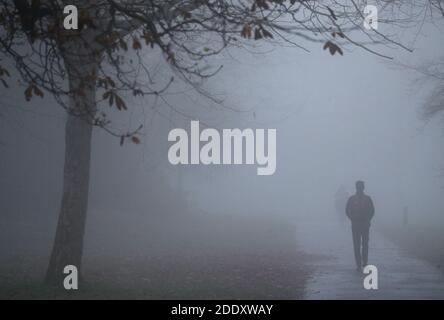 Im war Memorial Park in Basingstoke, Hampshire, ziehen sich die Menschen durch den Nebel. Stockfoto