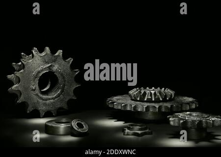 Zahnräder, Lager und andere Metallteile auf dem schwarzen Hintergrund Stockfoto
