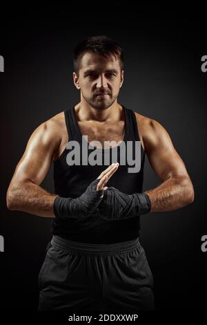 Muskulös sportlich schöner Mann im Boxverband auf schwarzem Hintergrund Stockfoto