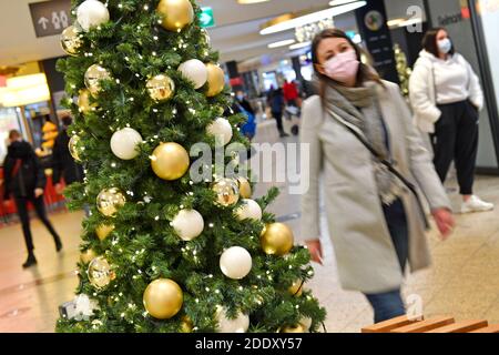 Thema Bild Gefangene in der Coronavirus-Pandemie am 26. November 2020. Eine junge Frau mit Gesichtsmaske, Maske geht in einem Einkaufszentrum an einem Weihaftertsbaum vorbei. Pandemie, Sperrung, Abschaltung, Inzidenzwert. MODELL FREIGEGEBEN! Weltweite Nutzung Stockfoto