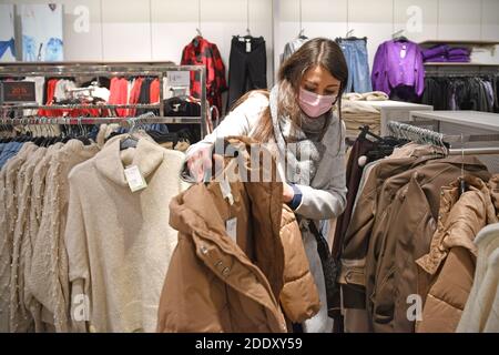 Themenbild SCHWARZ FREITAG am 26. November 2020. Eine junge Frau mit Gesichtsmaske, Maske schaut auf Textilien, Kleidungsstücke in einem Modegeschäft in Zeiten der Corona-Pandemie, Sperrung, Abschaltung, Inzidenzwert. MODELL FREIGEGEBEN! Weltweite Nutzung Stockfoto