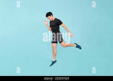 Voller Körper von energischen jungen Athleten asiatischen Mann springen in Hellblauer Studiohintergrund Stockfoto