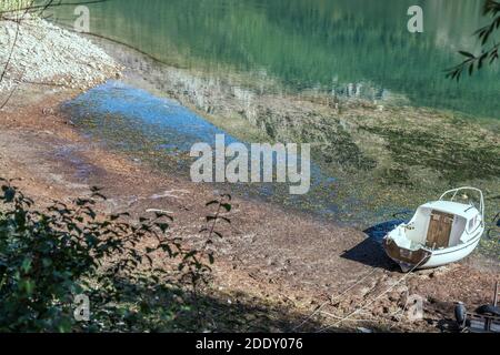 Landschaft mit Boot an Land und Berge spiegeln sich in klarem Wasser des Sees Scanno, in hellem Licht in der Nähe Apppenninia, L'Aquila, Abruzzen, Italien Stockfoto