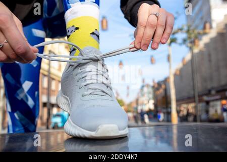 Weibliche Fitness-Läuferin, die Sportschuhschnüren bindet. Nahaufnahme von Händen und Beinen. Stockfoto