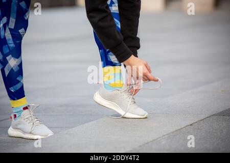 Weibliche Fitness-Läuferin, die Sportschuhschnüren bindet. Nahaufnahme von Händen und Beinen. Stockfoto