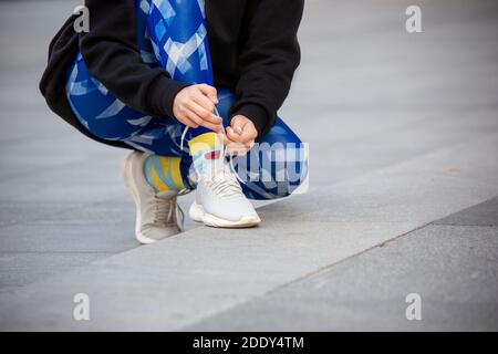 Weibliche Fitness-Läuferin, die Sportschuhschnüren bindet. Nahaufnahme von Händen und Beinen. Stockfoto