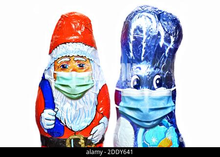 Weihnachtsmann und Osterhase Schokolade Figuren tragen Gesichtsmasken Stockfoto