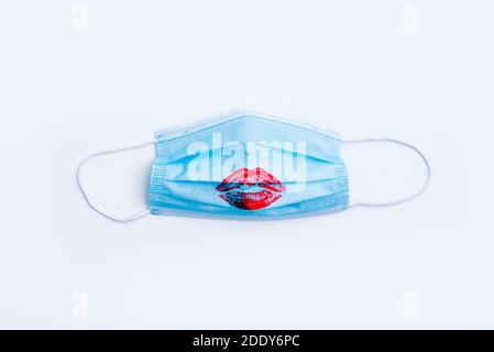 Chirurgische Schutzmaske mit roten Lippenstift-Lippen auf weißem Hintergrund. Blaue medizinische Maske zum Schutz gegen Influenza, Coronavirus und andere Viren