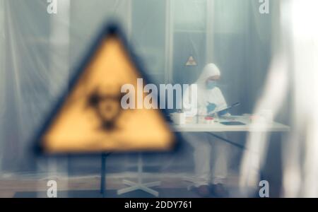 Wissenschaftlerinnen mit bakteriologischem Schutzanzug untersuchen im Labor hinter einem Schutzvorhang. Selektiver Fokus auf Wissenschaftler im Bac Stockfoto