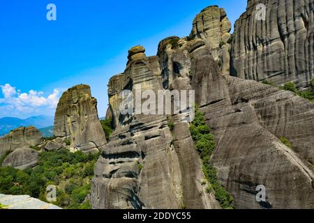 Meteora Land im Himmel: Große alte Stadt von Meteora in Griechenland. Bäume, alte Häuser, blauer Himmel und weiße Wolken. Stockfoto