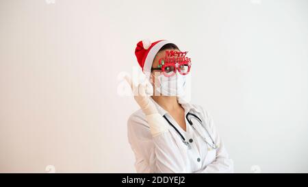 Kaukasische Frau Arzt während der Weihnachts-und Neujahrsferien mit einem Finger in einem Gummihandschuh zeigt auf Platz für Text kopieren. Stockfoto