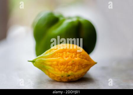 Gelbe bittere Kürbis zwischen grünen Paprika mit isoliertem Hintergrund, ungerade heraus Stockfoto