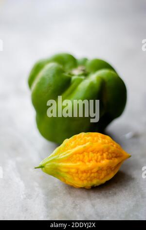 Gelbe bittere Kürbis zwischen grünen Paprika mit isoliertem Hintergrund, ungerade heraus Stockfoto