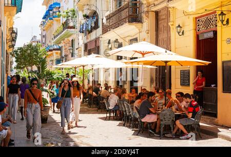 Havanna, Kuba - 26. Juli 2018: Eine Straße mit Tischen unter Sonnenschirmen vor Restaurants für Touristen und Einheimische, um ihren Tag zu genießen. Stockfoto