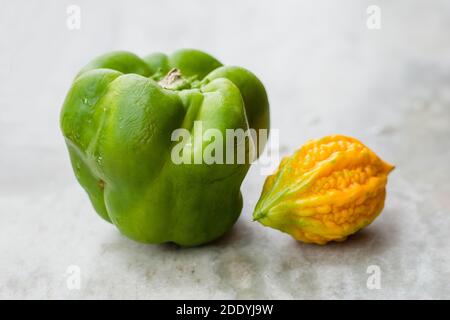 Gelbe bittere Kürbis zwischen grünen Paprika mit isoliertem Hintergrund, ungerade heraus Stockfoto