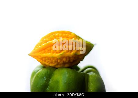 Gelbe bittere Kürbis zwischen grünen Paprika mit isoliertem Hintergrund, ungerade heraus Stockfoto