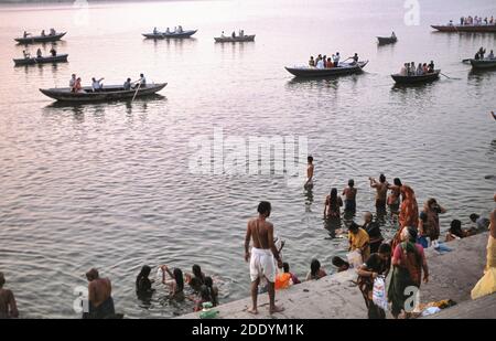 24.03.2010, Varanasi, Uttar Pradesh, Indien, Asien - Blick von einem Ghat am Ufer entlang des heiligen Ganges auf Leute, die im Fluß mit Ruderbooten baden. Stockfoto