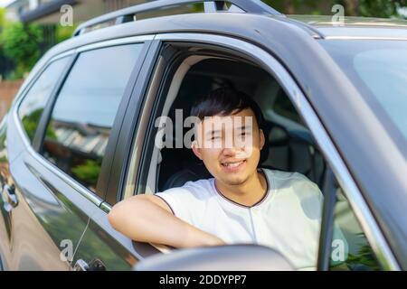 Asiatische glücklich junge gut aussehende Mann fahren ein Auto in Vordersitz mit Lächeln bereiten Sie sich auf die Reise mit seinem Auto. Stockfoto