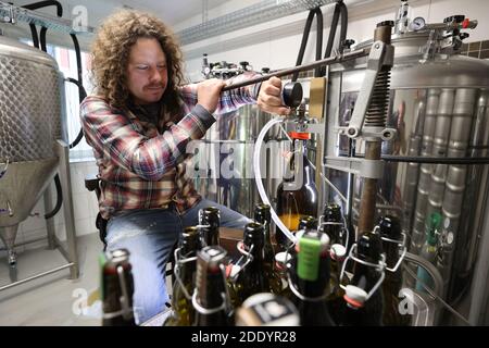 Gera, Deutschland. November 2020. Bierbrauer Kevin Pagenkopf füllt in seiner Showbrauerei selbstgebrautes dunkles Bier in eine Flasche. Neben Pils, Hellem und Dark Lager werden auch andere traditionelle Biere gebraut, wie Märzen oder Bockbier, die vom Fass oder in Flaschen für den Hausgebrauch genossen werden können. Kredit: Bodo Schackow/dpa-zentralbild/dpa/Alamy Live Nachrichten Stockfoto