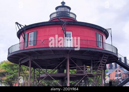 Der historische rot-schwarze Wahrzeichen 7 Fuß Hügel Leuchtturm im inneren Hafen in baltimore maryland an einem bewölkten Tag. Stockfoto