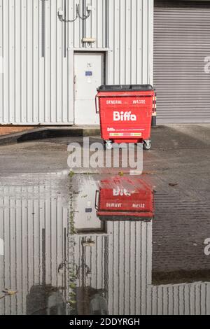 BIFFA Industrie-Mülltonne auf Werksgelände mit Reflexionen im Wasser. Für die industrielle Abfallwirtschaft, Wasserreflexionen, Werksstandort Großbritannien. Stockfoto