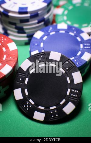 Verschiedene Poker spielen Chips auf einem grünen Tisch vor schwarzem Hintergrund. Online-Gaming. . Hochwertige Fotos Stockfoto