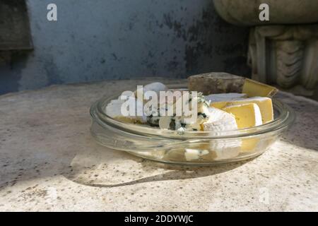 Verschiedene Arten von köstlichen Käse in Glasplatte auf Stein Tisch sortiert. Vintage-Style. Stockfoto