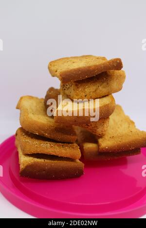 Stapel von trockenem Toast auf Kunststoffplatte. Nahaufnahme Stapel gerösteter Brotscheiben. Toastbrot auf weißem Hintergrund. Stockfoto