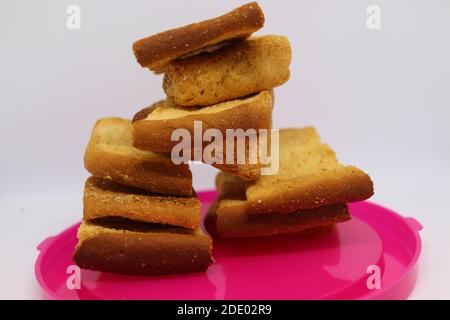 Stapel von trockenem Toast auf Kunststoffplatte. Nahaufnahme Stapel gerösteter Brotscheiben. Toastbrot auf weißem Hintergrund. Stockfoto