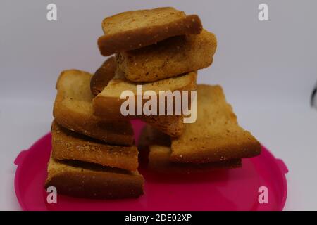 Stapel von trockenem Toast auf Kunststoffplatte. Nahaufnahme Stapel gerösteter Brotscheiben. Toastbrot auf weißem Hintergrund. Stockfoto