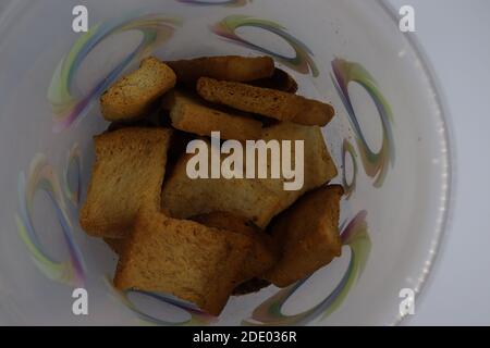 Stapel von trockenem Toast auf Kunststoffplatte. Nahaufnahme Stapel gerösteter Brotscheiben. Toastbrot auf weißem Hintergrund. Stockfoto