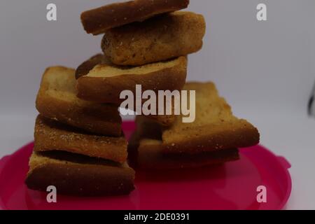 Stapel von trockenem Toast auf Kunststoffplatte. Nahaufnahme Stapel gerösteter Brotscheiben. Toastbrot auf weißem Hintergrund. Stockfoto