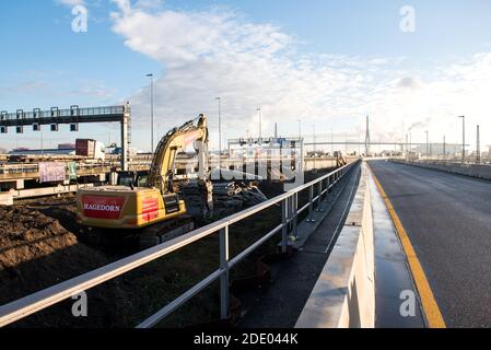 Hamburg, Deutschland. November 2020. Ein Bagger steht an der Autobahn A7 bei Waltershof. Auf der rechten Seite sehen Sie einen neuen temporären hohen Damm mit zwei Spuren. Mit einem symbolischen Spatenstich am Freitag ging der Ausbau der Autobahn A7 südlich des Hamburger Elbtunnels in eine wichtige Phase. Quelle: Daniel Bockwoldt/dpa/Alamy Live News Stockfoto