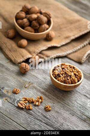 Frische Walnusskerne und ganze Walnüsse in einer Schüssel auf rustikalem alten Holztisch. Gesunde Bio-Lebensmittel, Bio-Weingärten, natürlichen Hintergrund. Speicherplatz für Ihren kopieren Stockfoto