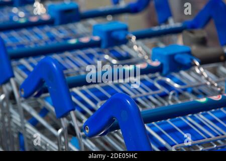 Nahaufnahme der blauen Supermarkt Trolleys bereit für den Einsatz draußen Ein großer Supermarkt in Großbritannien in einem Einkaufszentrum Stockfoto