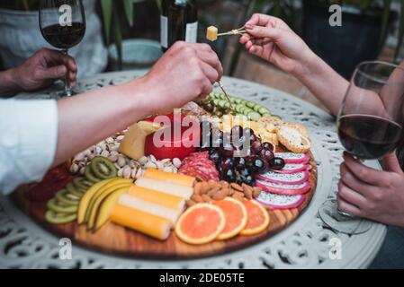 Eine Nahaufnahme von Leuten, die von einer köstlichen Wurstwaren essen Brett mit Käse und Obst Stockfoto