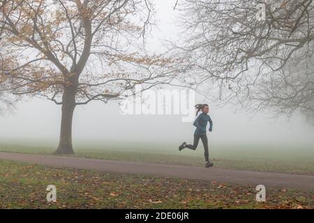 Cambridge, Großbritannien. November 2020. Ein Morgenjogger läuft durch dichten Nebel auf Jesus Green. Alan Copson/Alamy Live News Stockfoto