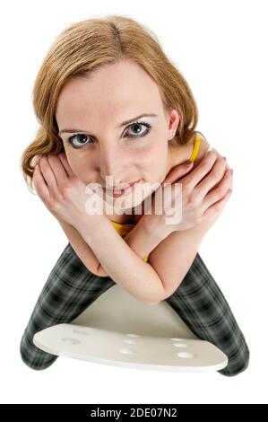 Weitwinkel extrem hohe volle Länge Ansicht eines jungen Blonde Frau sitzt links auf einem Stuhl mit gekreuzten Armen Vor ihrer Brust, die freundlich anschaut Stockfoto