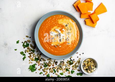 Kürbiscremesuppe mit Blauschimmelkäse und Samen in der Schüssel auf weißem Grund. Draufsicht Stockfoto