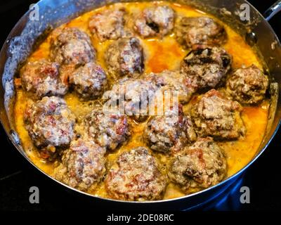 Fleischbällchen werden in Tomate und Sahne Sauce in Topf geschmort Zu Hause Küche Stockfoto