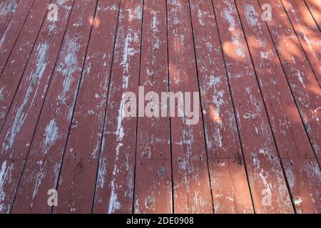 Nahaufnahme von kastanienfarbenen hölzernen Terrassendielen, die einen neuen Anstrich benötigen. Stockfoto