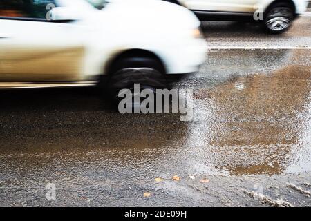 Nasse Stadtstraße nach Schmelzen des ersten Schnees und verschwommen In Bewegung Autos am Herbsttag Stockfoto